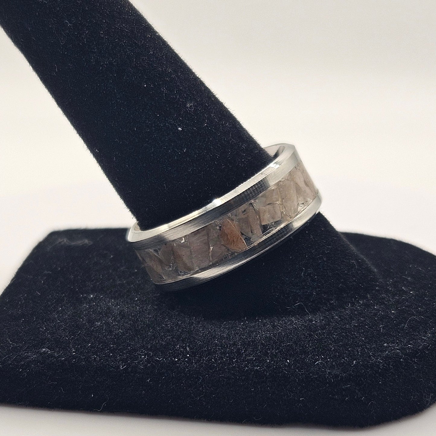 Silver ring on a black stand against a white background