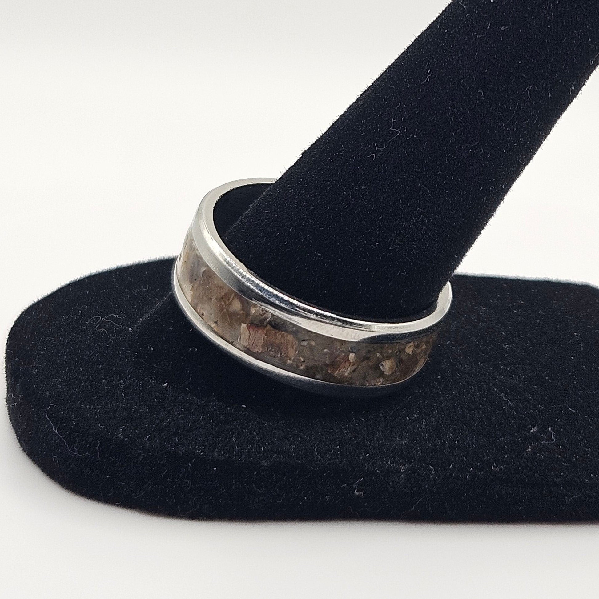 Silver ring on a black velvet stand against a white background