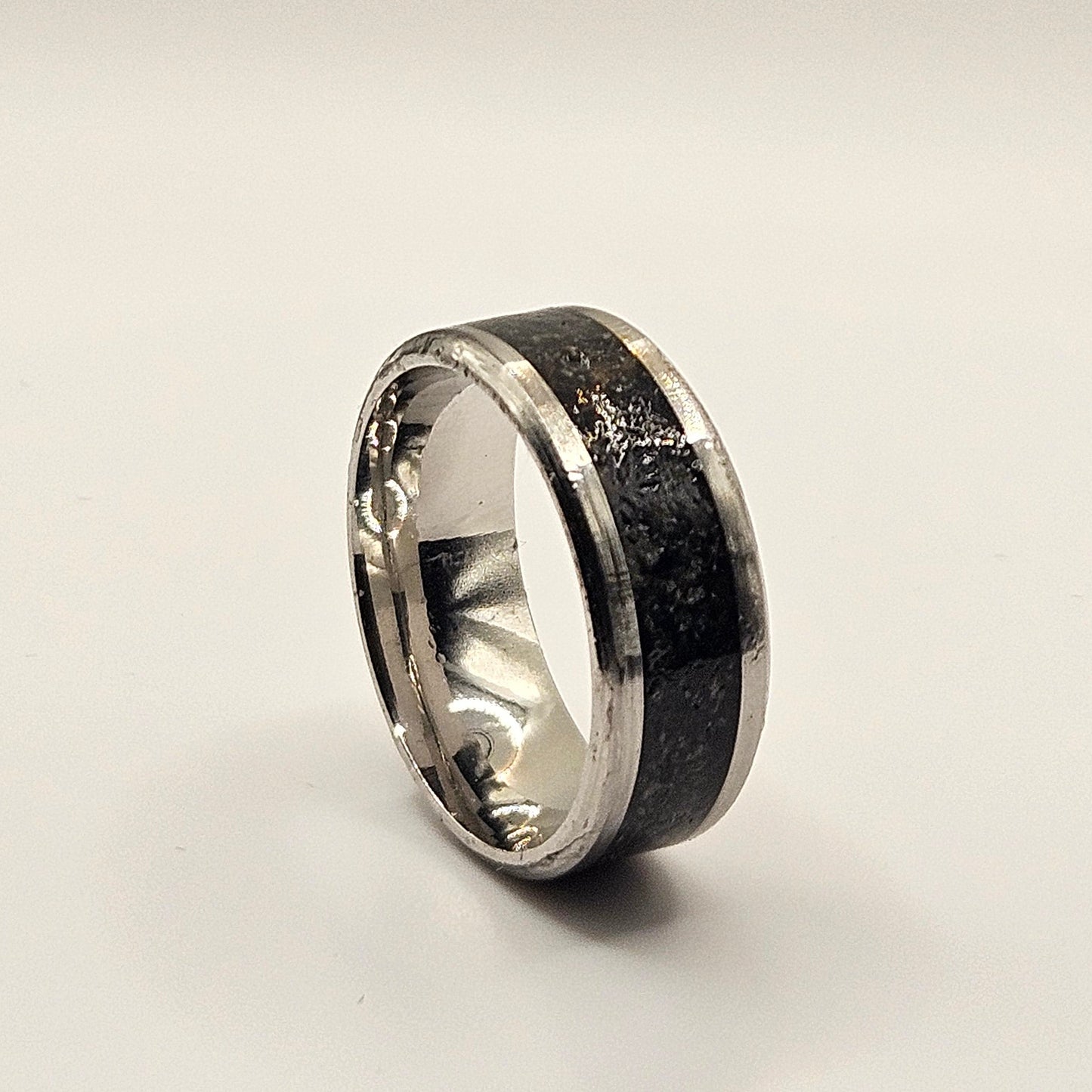 Silver ring with black interior on a light gray background