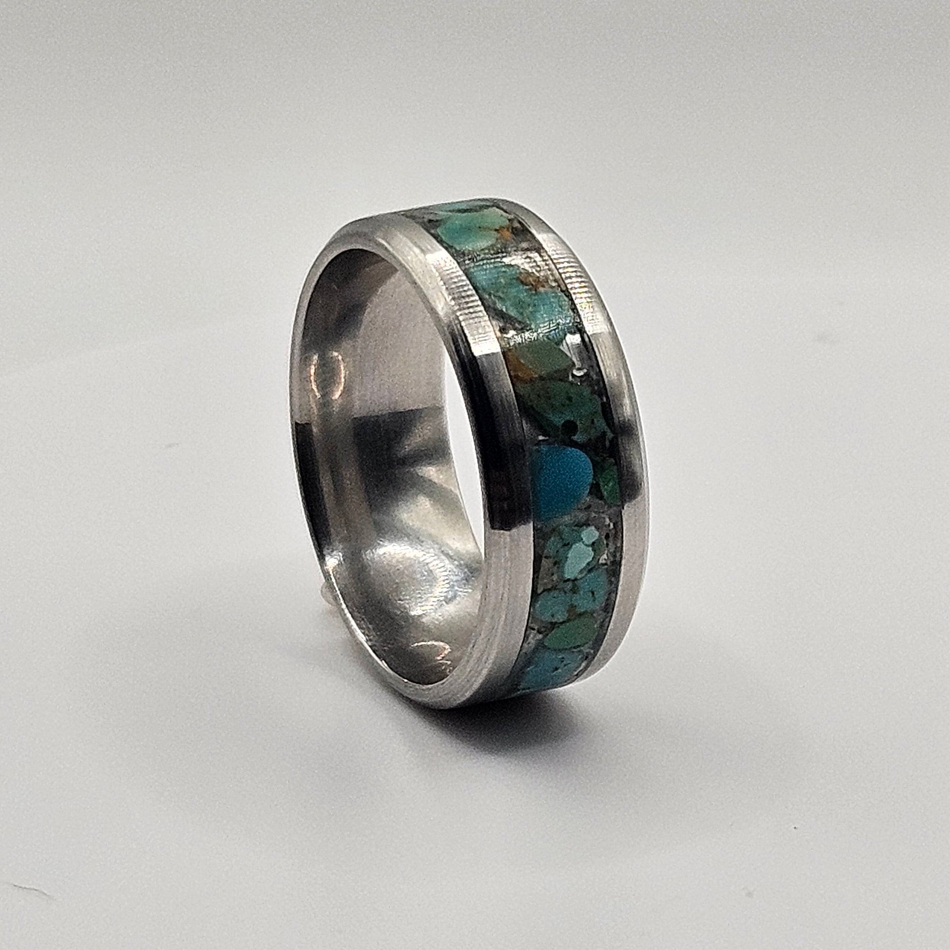 Silver ring with embedded greenstone on a white background