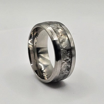 Silver ring with embedded stones on a light gray background