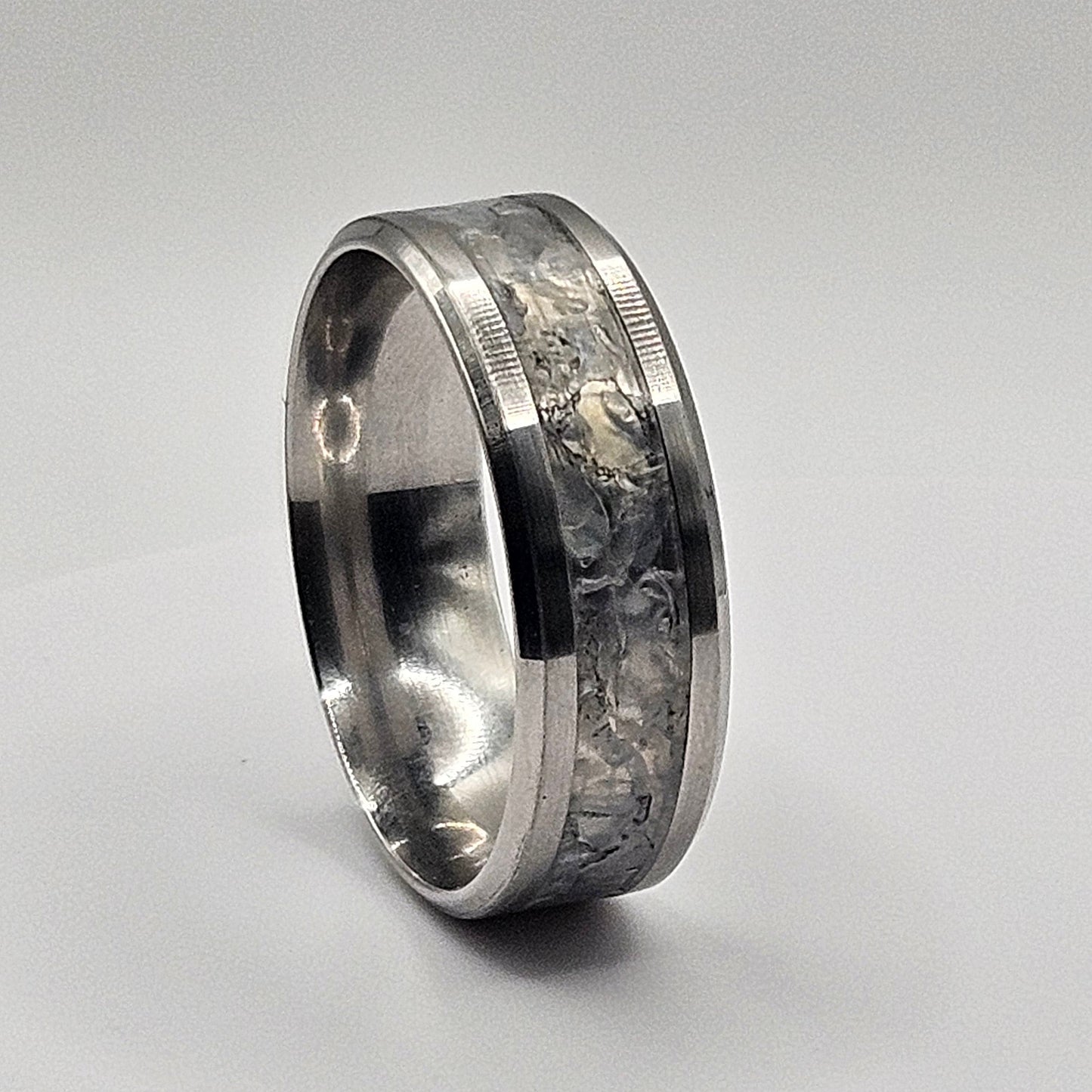 Silver ring with a clear stone inlay on a light gray background