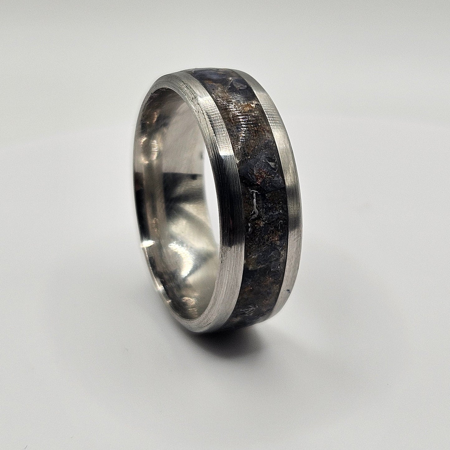 Silver ring with a dark blue inlay on a light gray background