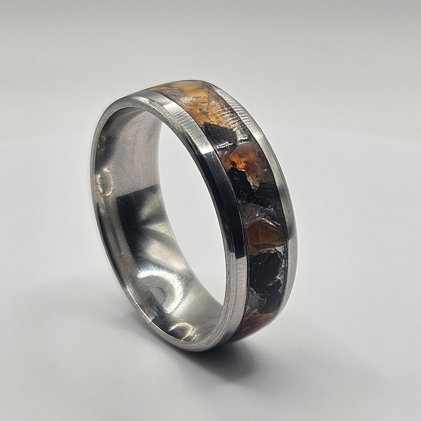 Silver ring with embedded material on a light gray background