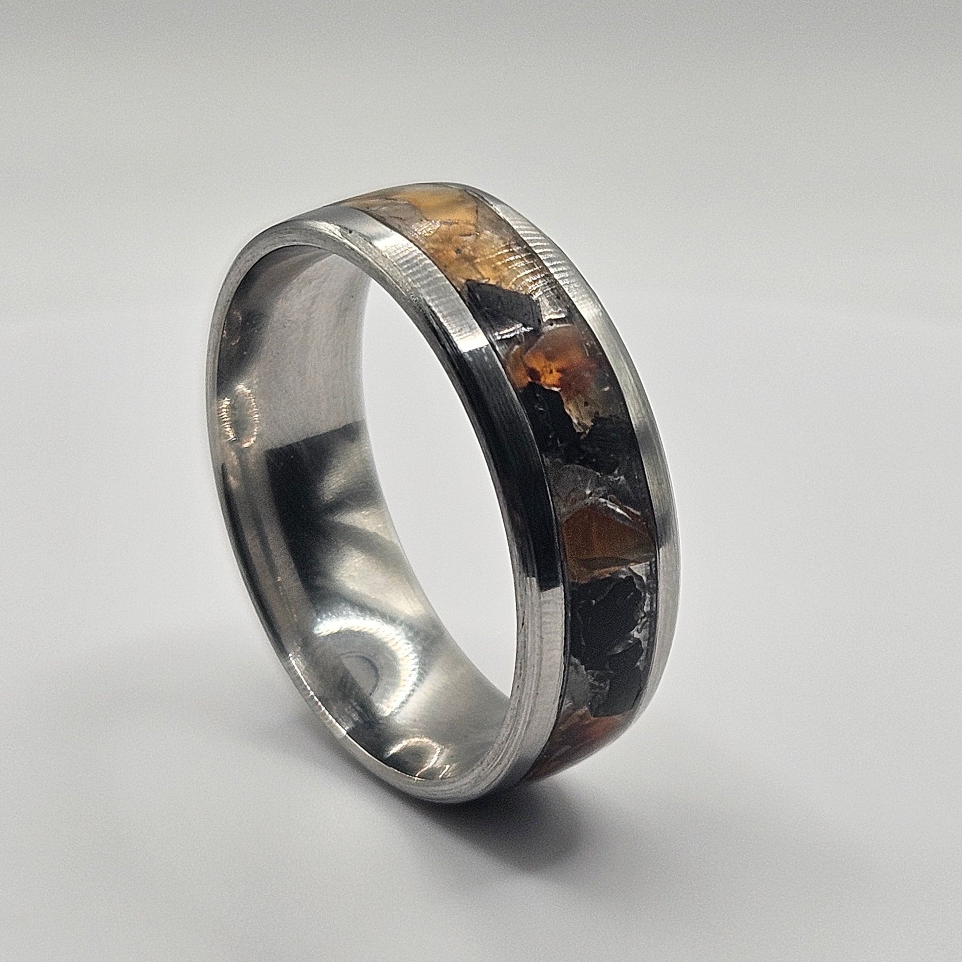 Silver ring with embedded material on a light gray background