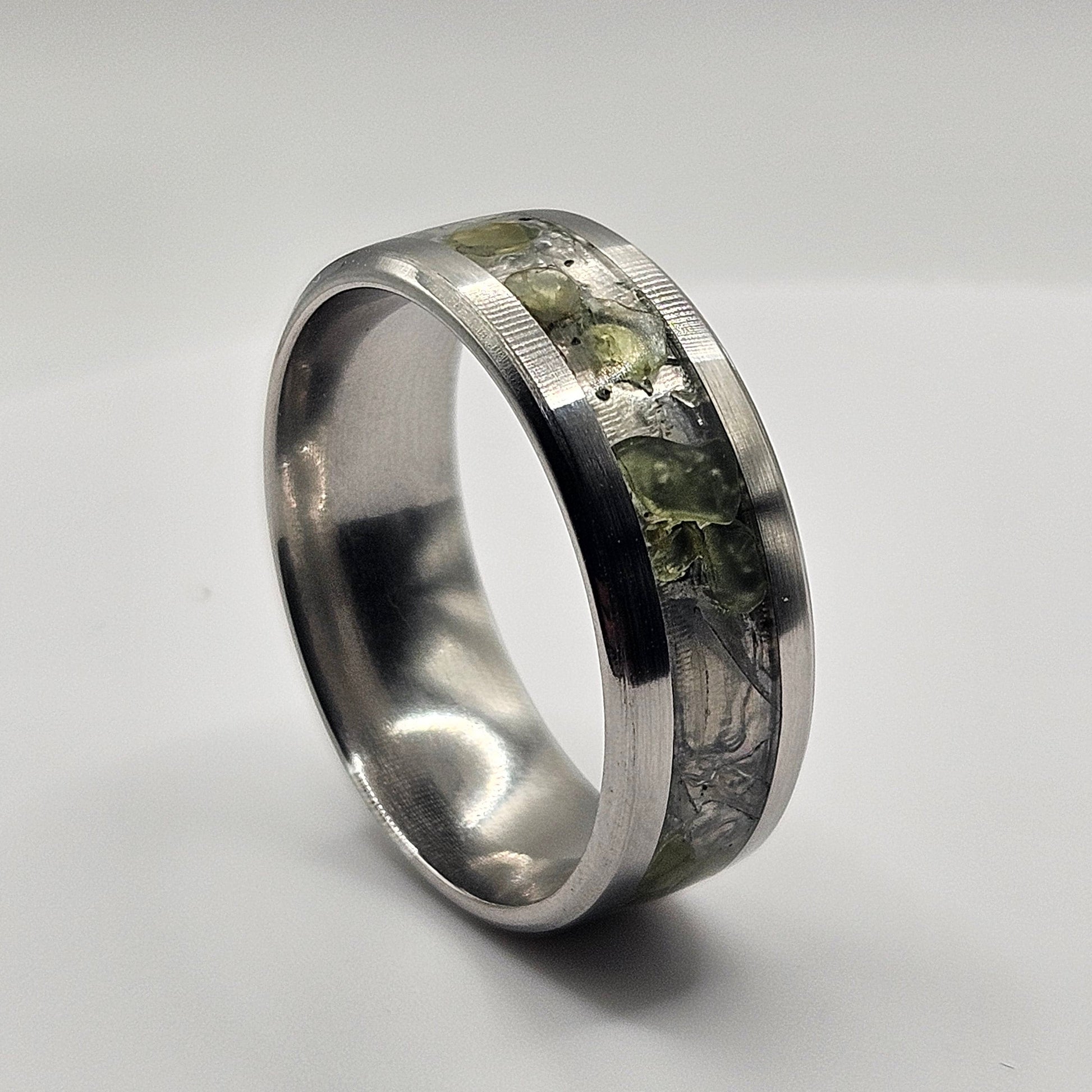 Silver ring with embedded material on a light gray background
