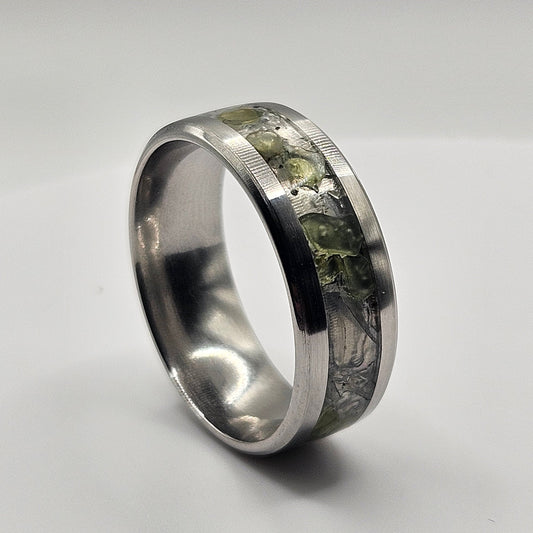Silver ring with embedded material on a light gray background