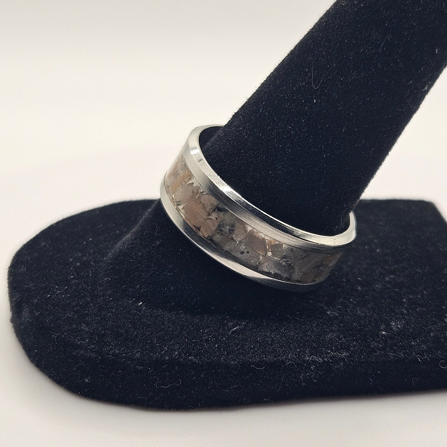 Silver ring on a black velvet stand against a white background