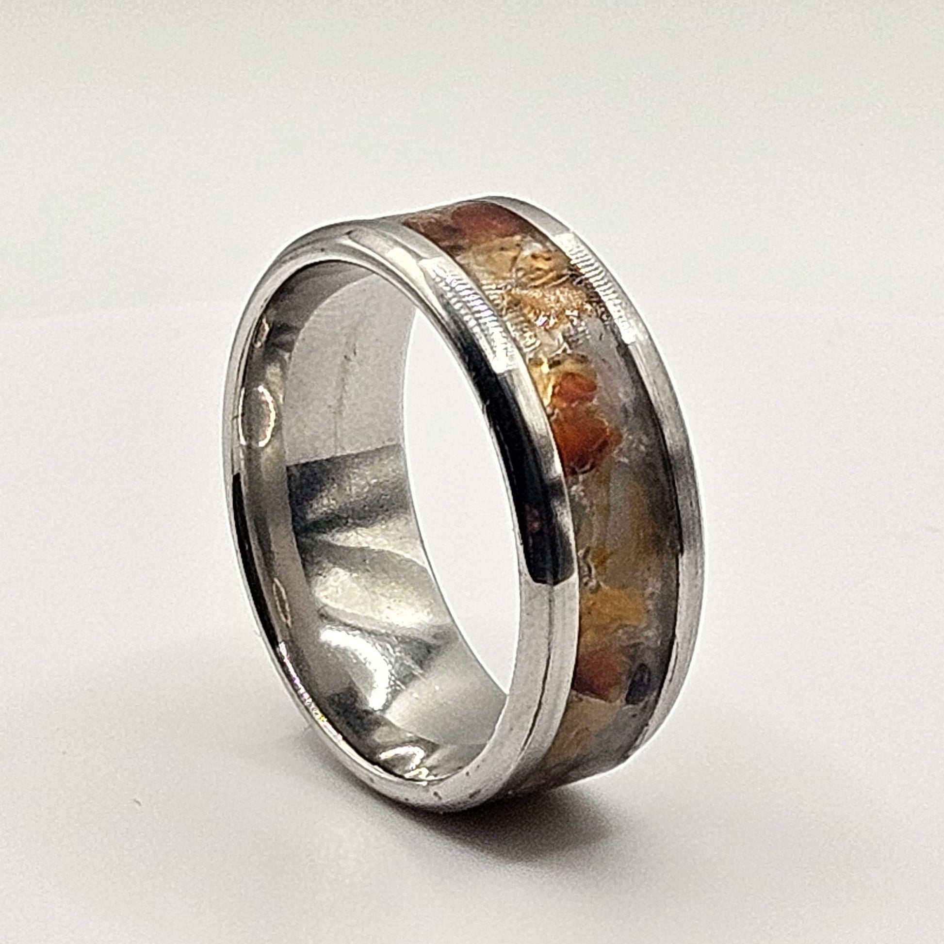 Silver ring with embedded material on a light gray background