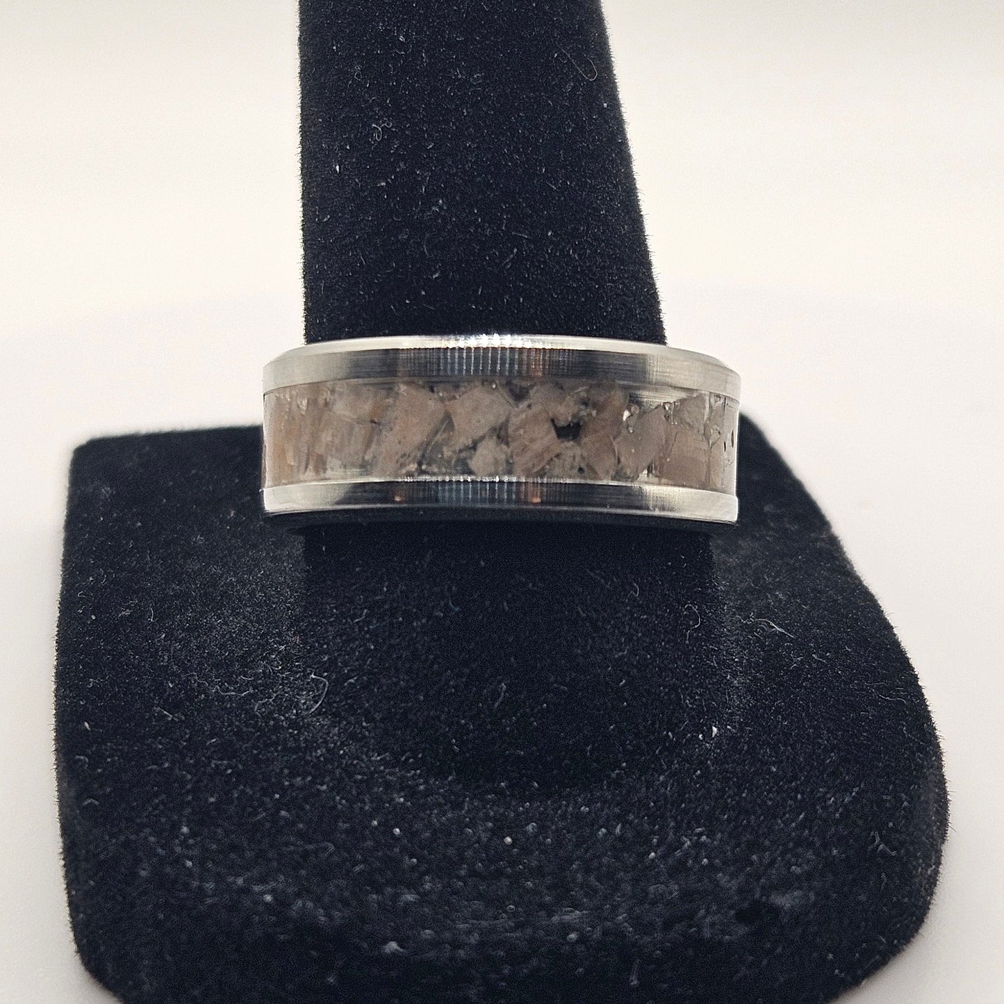 Silver ring on a black stand against a white background