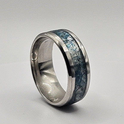 Silver ring with blue gemstone inlay on a light gray background