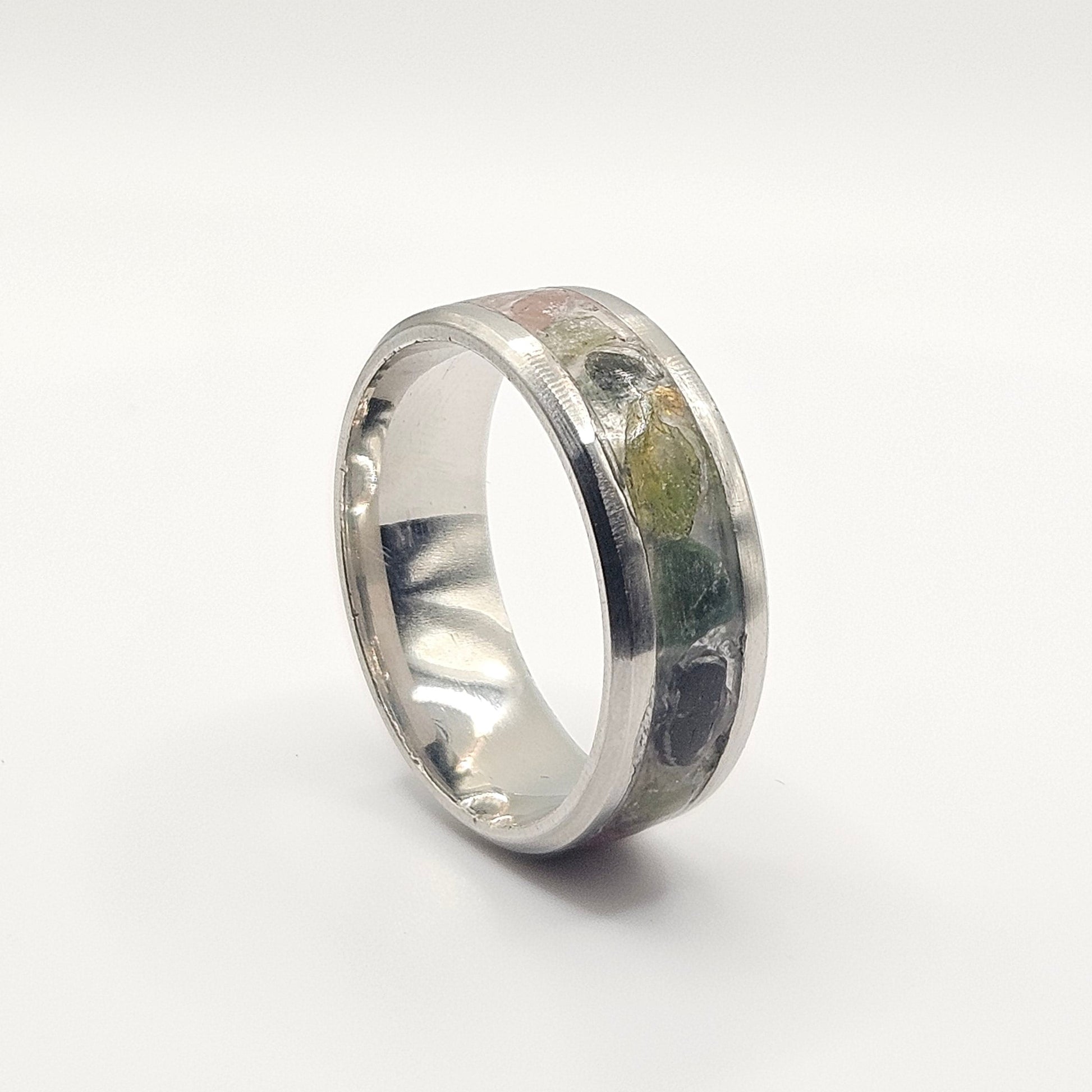 Silver ring with embedded green stone on a white background